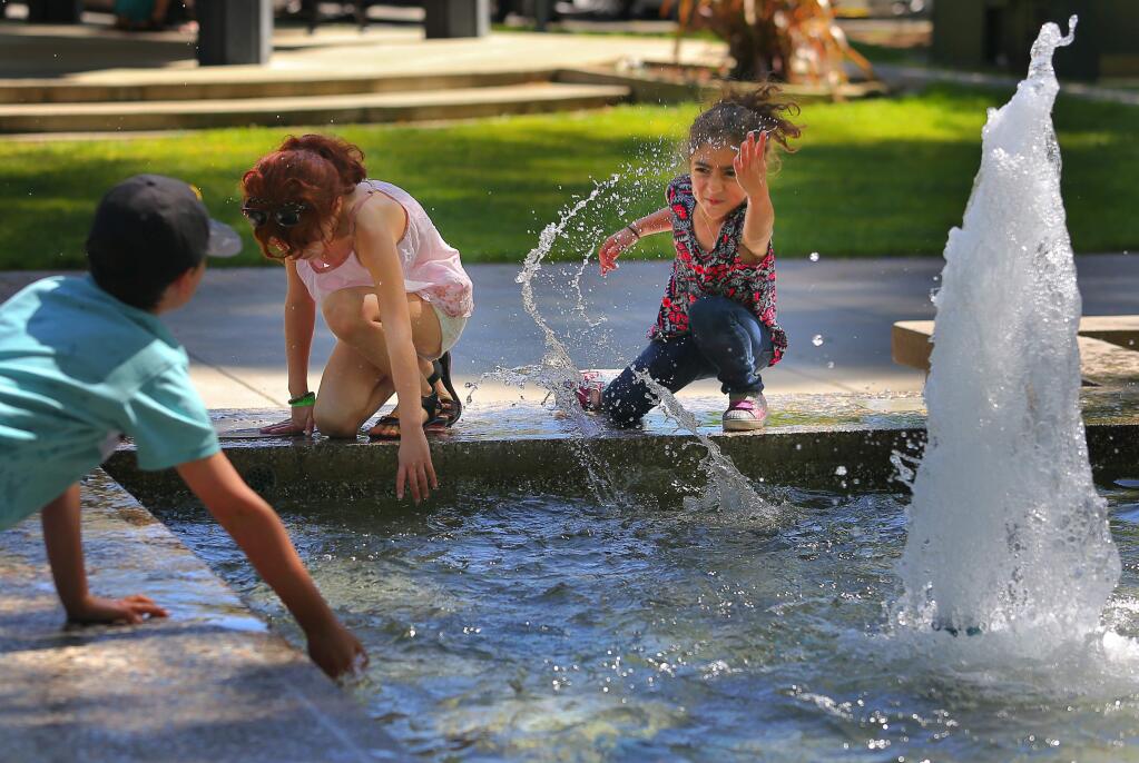 Palig Horoupian, 6, right, tries to splash Areg Horoupian, 10, left, while Pateel Horoupian dips her hand in the fountain in Healdsburg Plaza on Wednesday, April 6, 2016. (Christopher Chung/ The Press Democrat)