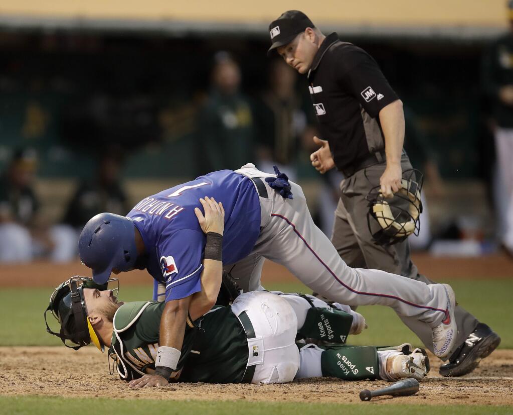 Texas Rangers' Elvis Andrus, top, collides with Oakland Athletics catcher Chris Herrmann in the seventh inning of a baseball game Saturday, July 27, 2019, in Oakland, Calif. Andrus was out on the play. (AP Photo/Ben Margot)