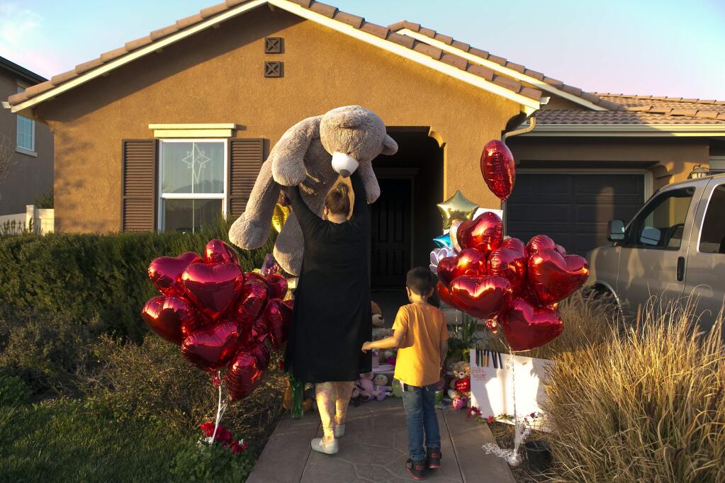 FILE--In this Jan. 18, 2018, file photo, neighbor Liza Tozier, and her son, Avery Sanchez, 6, drop off his large 'Teddy' as a gift for the children who lived on a home where police arrested a couple accused of holding 13 children captive in Perris, Calif., More than $120,000 has been donated to help the 13 siblings who authorities say were kept chained to beds for months by their parents and starved so much that their growth was stunted. (AP Photo/Damian Dovarganes, file)