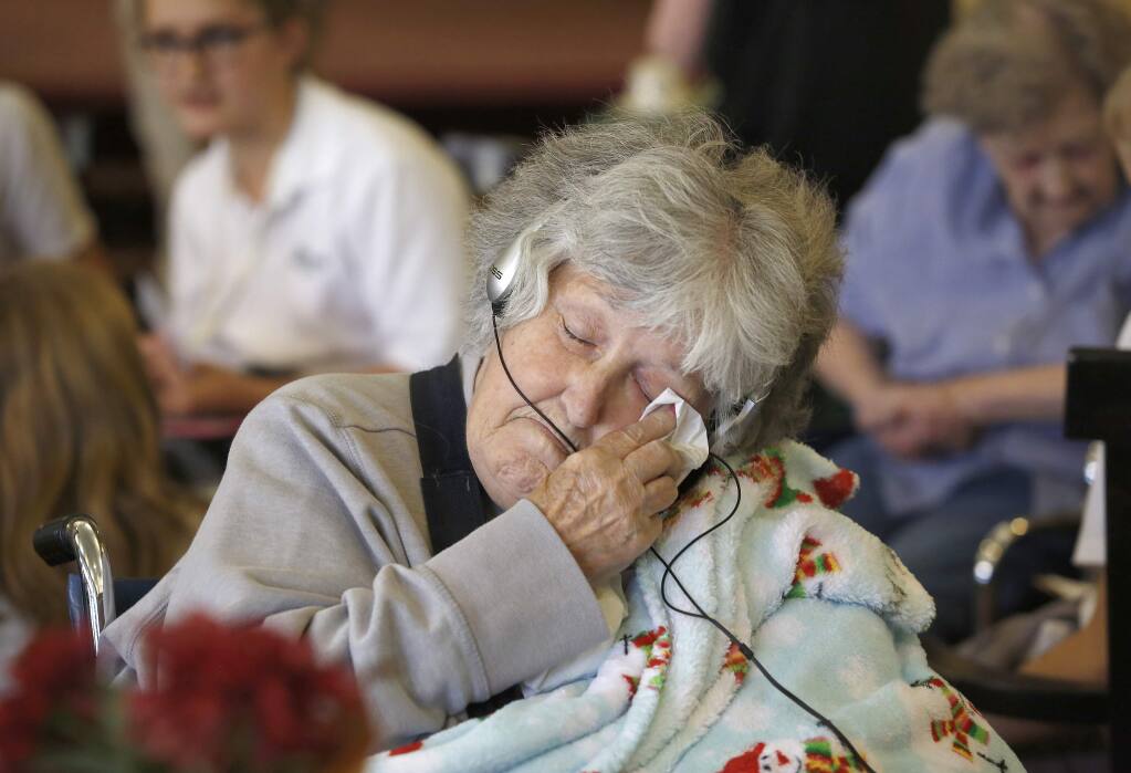 Dolores Kovocovich wipes away a tear while listening to music provided by The Healdsburg School students at Healdsburg Senior Living. (Beth Schlanker / The Press Democrat)
