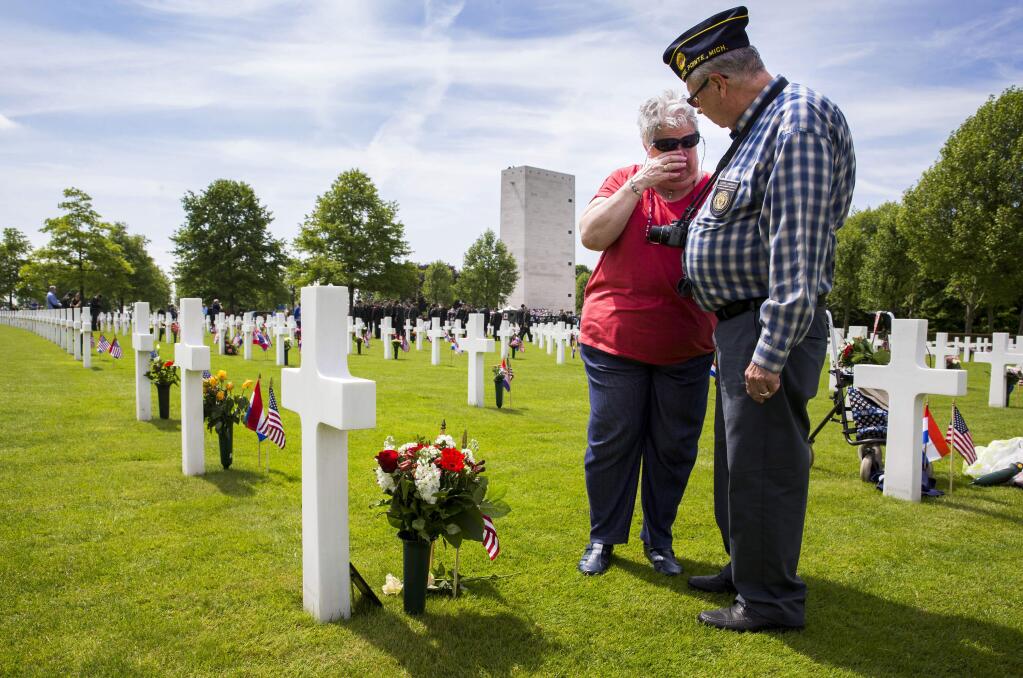 Mary Ann Herbst from St. Paul, Minnesota, left, visits the grave of her father Pfc. John Stephens, from Iowa, for the first time together with her husband Carl, right, prior to a solemn Memorial Day commemoration service in Margraten, southern Netherlands, Sunday May 24, 2015, marking the 70th anniversary of the end of World War II. Mary Ann, born Nov. 13, 1944, never knew her father who fell on April 18, 1945. Thousands of people attended Sunday's ceremony at the American cemetery, a manicured patch of 65.5 acres (26.5 hectares) that contains 8,301 headstones. (AP Photo/Vincent Jannink)