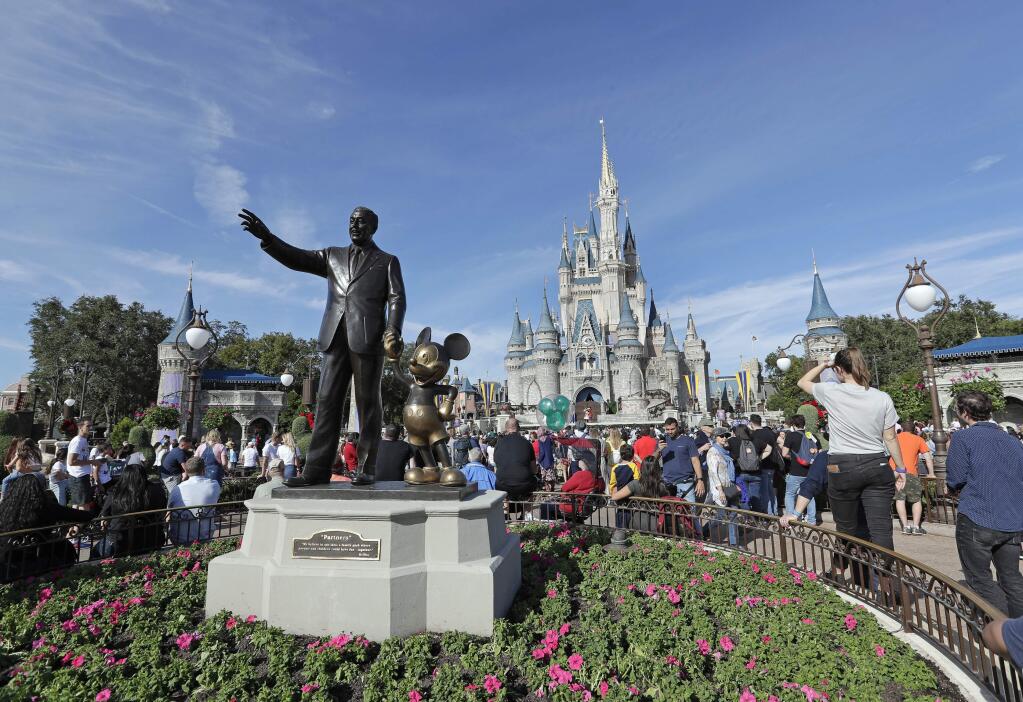 FILE - In this Jan. 9, 2019, file photo, theme park guests walk near a statue of Walt Disney and Mickey Mouse in front of the Cinderella castle in the Magic Kingdom at Walt Disney World in Lake Buena Vista, Fla. Disney said Tuesday, Sept. 24, that plant-based meals would be available at all of its restaurants and quick-meal hubs at Walt Disney World in Florida and Disneyland Resort in California.(AP Photo/John Raoux, File)