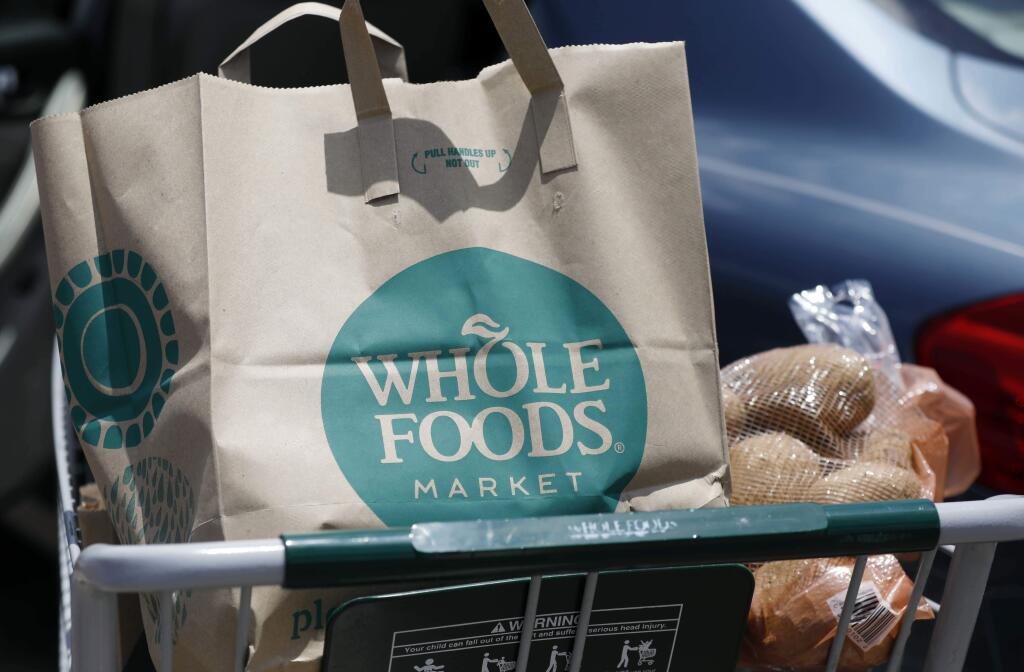A Whole Foods Market purchase awaits placement in a car trunk, outside the Jackson, Miss., store Friday, June 16, 2017. Amazon is buying Whole Foods in a stunning move that gives it hundreds of stores across the U.S., a brand-new laboratory for radical retail experiments that could revolutionize the way people buy groceries. (AP Photo/Rogelio V. Solis)