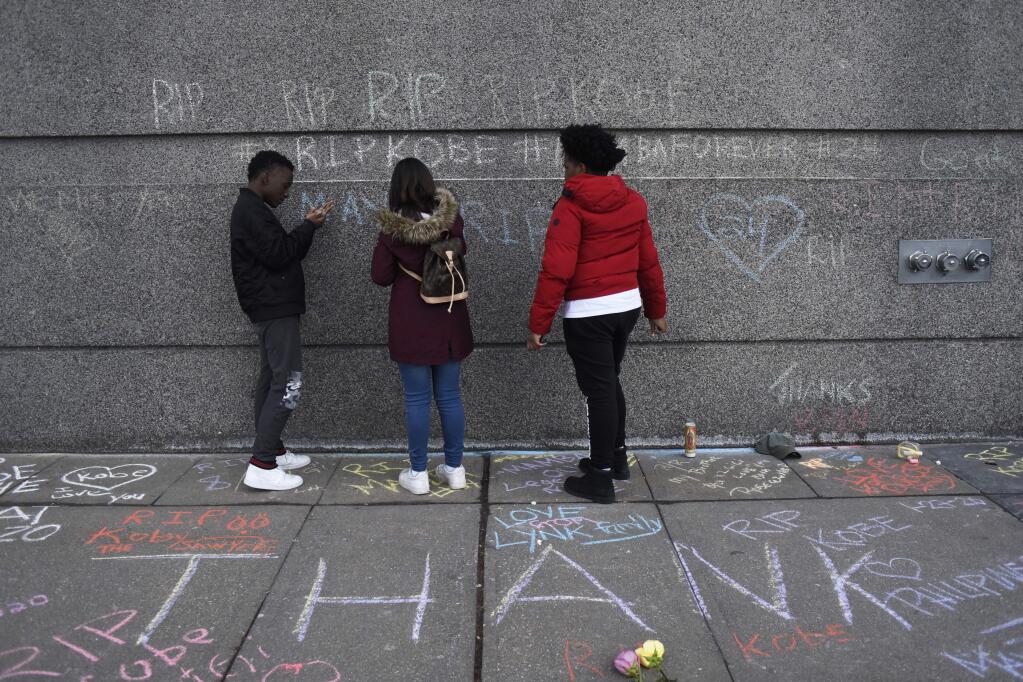 Students from the Suder Montessori school write on the outside of the United Center with a tribute to Kobe Bryant before an an NBA basketball game between the Chicago Bulls and the San Antonio Spurs Monday, Jan. 27, 2020, in Chicago. (AP Photo/David Banks)