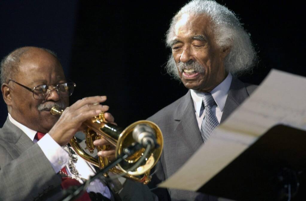 In this Feb. 28, 2003 file photo, jazz trumpeter and former Navy band member Clark Terry, left, plays under the watchful eye of guest conductor Gerald Wilson, also a former Navy band member, at a concert at the Great Lakes Naval Training Center in Great Lakes, Ill. Wilson, the dynamic jazz big band leader, composer and arranger whose career spanned more than 75 years, died Monday, Sept. 8, 2014. He was 96. (AP Photo/Brian Kersey, File)