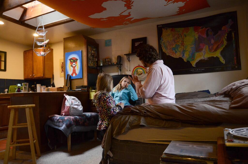 FILE - In this Nov. 28, 2017, file photo, TC Bell sits with his two daughters Dagny, and Emma, before they get dressed for school, at their home in Denver. Bell's daughters were then recipients of the Children's Health Insurance Program or CHIP, which is a program that provides low-cost coverage to families who earn too much to qualify for Medicaid. Health care proposals are among the first actions for some new Democratic governors and Democratically controlled legislatures. (AP Photo/Tatiana Flowers, File)