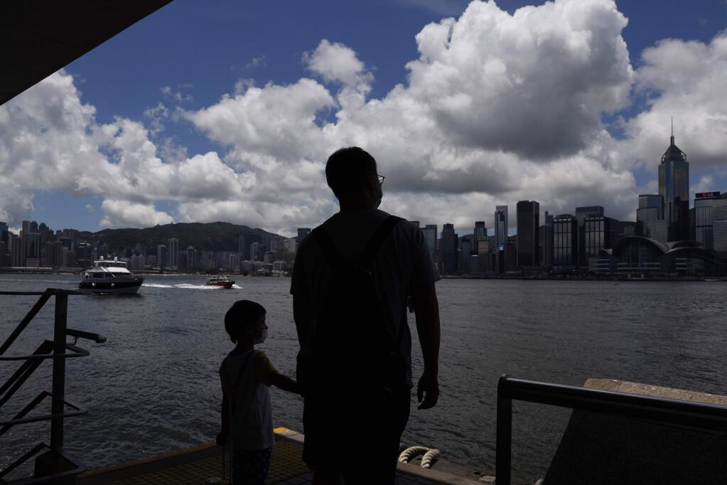 People walk at the waterfront of the Victoria Harbor of Hong Kong, Saturday, June 20, 2020. China's top legislative body has taken up a draft national security law for Hong Kong that has been strongly criticized as undermining the semi-autonomous territory's legal and political institutions. (AP Photo/Kin Cheung)