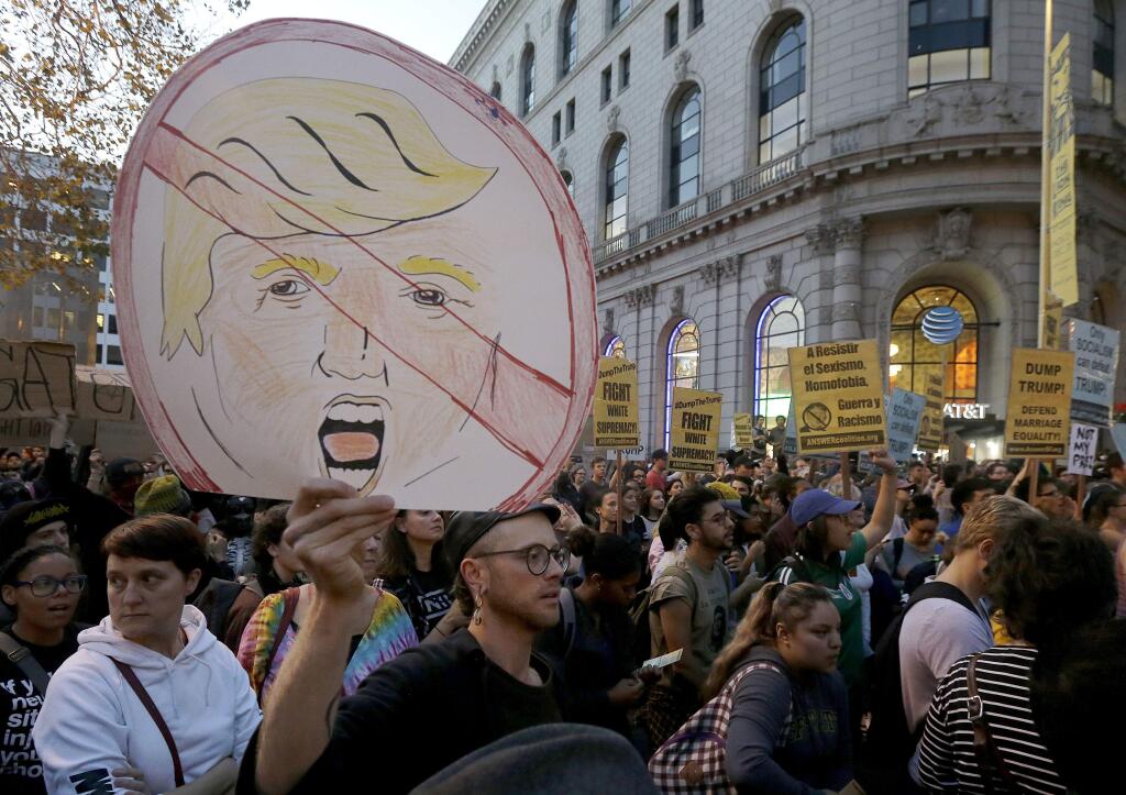 Protesters hold up signs during a demonstration in opposition of Donald Trump's presidential election victory in San Francisco, Wednesday, Nov. 9, 2016. (AP Photo/Jeff Chiu)