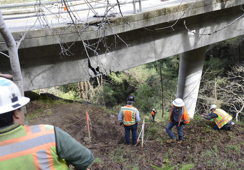 In this Wednesday, Feb. 22, 2017 photo, Caltrans engineers evaluate storm damage near a large crack on the Pfeiffer Canyon Bridge on Highway 1 in Big Sur, Calif. The bill to repair California's roadways hammered by floods and rockslides in an onslaught of storms this winter has reached nearly $600 million, more than double what the state budgeted for such emergencies, and the costs are mounting for other badly damaged infrastructure just two months into 2017. On the rain-soaked coast in Central California, the Pfeiffer Canyon Bridge has crumble beyond repair, blocking passage on the north-south Highway 1 route for up to a year. Until it is rebuilt, visitors can drive up to view the roughed coastline, then turn back. (David Royal /The Monterey County Herald via AP)