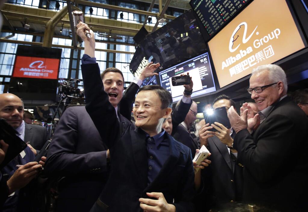 Jack Ma, center, founder of Alibaba, raises a ceremonial mallet before striking a bell during the company's IPO at the New York Stock Exchange, Friday, Sept. 19, 2014 in New York. (AP Photo/Mark Lennihan)