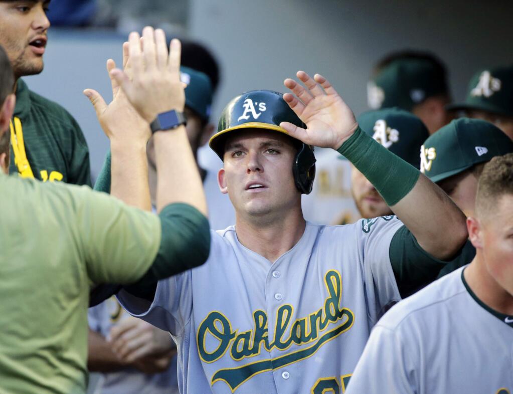 The Oakland Athletics' Ryon Healy is congratulated in the dugout after scoring on a single by Jaycob Brugman during the second inning against the Seattle Mariners, Saturday, July 8, 2017, in Seattle. (AP Photo/John Froschauer)