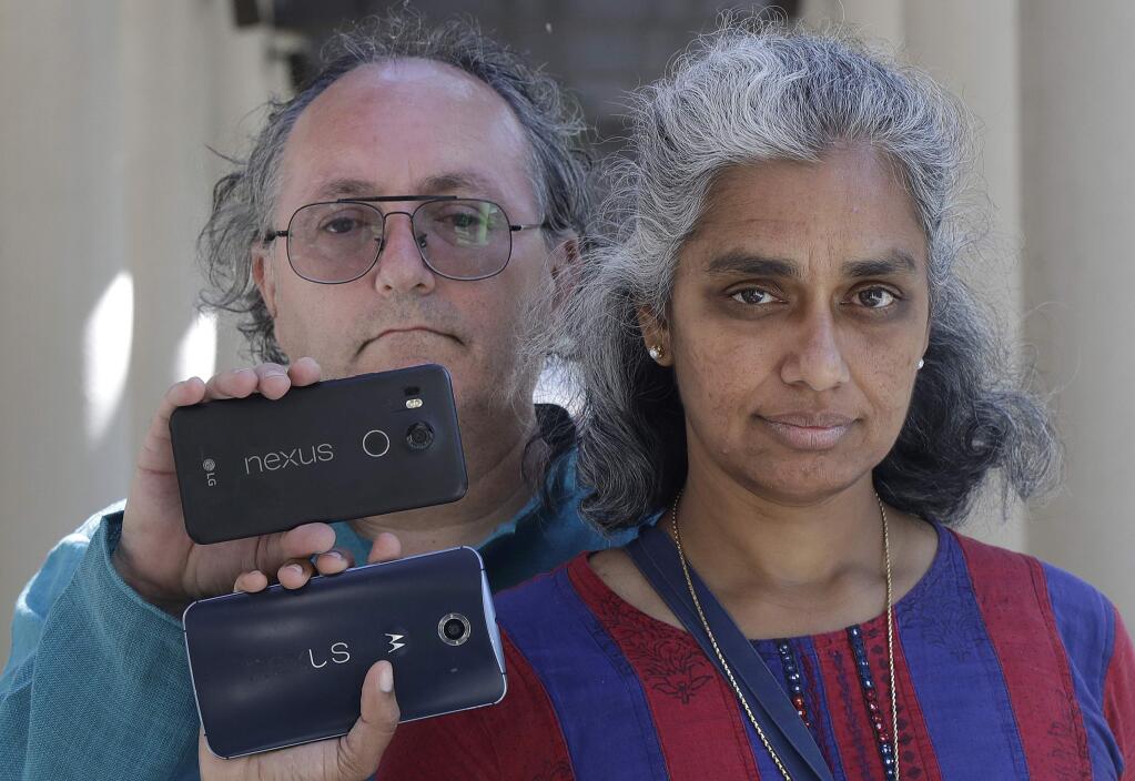In this July 25, 2018 photo, Kalyanaraman Shankari, right, and her husband Thomas Raffill hold their phones while posing for photos in Mountain View, Calif. An Associated Press investigation shows that using Google services on Android devices and iPhones allows the search giant to record your whereabouts as you go about your day. Shankari, a graduate researcher at UC Berkeley who connects commuting patterns with urban planners, noticed that her Android phone prompted her to rate a shopping trip to Kohl's. That happened even though she had turned off Google's “location history” setting, which according to the company should prevent it from remembering where a user has been. (AP Photo/Jeff Chiu)