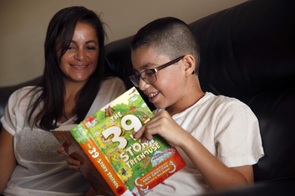 J.P. Sanchez, 10, who received a kidney in a transplant from his mother, Berta, reads a chapter of a book with her help for his summer school homework at their home in Rohnert Park , on Monday, July 6, 2015. (BETH SCHLANKER/ The Press Democrat)