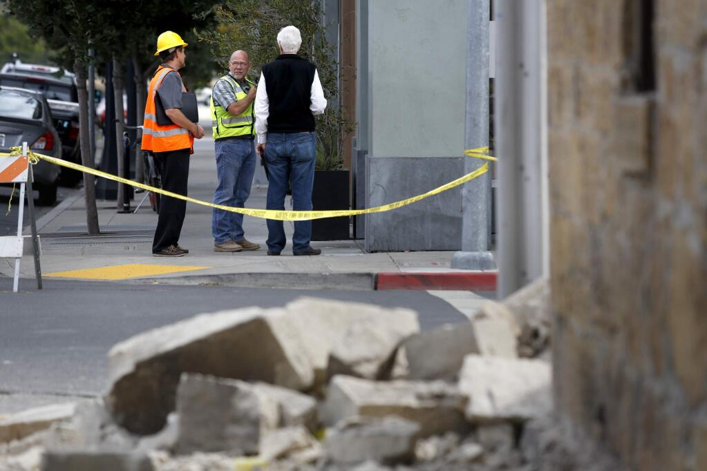 (From left) Structural engineer Lawrence Jones and general contractor Ed James help Doyle Wiseman evaluate the condition of his building Main Street West across from the severely damaged Pfeiffer Building building following Sunday's earthquake on Monday, August 25, 2014 in Napa, California. (BETH SCHLANKER/ The Press Democrat)