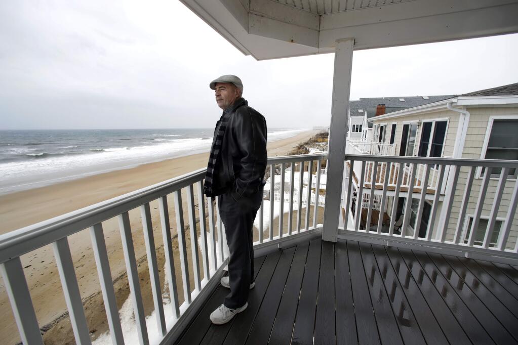 In this Feb. 15, 2019 photo, real estate agent Tom Saab stands on a oceanfront deck at a condo he developed in Salisbury, Mass. Academic researchers say concerns over rising sea levels and increased flooding are having subtle but significant impacts on coastal property values, finding that climate change concerns have sapped more than $15 billion in appreciation from homes along the Eastern Seaboard and Gulf Coast. (AP Photo/Elise Amendola)