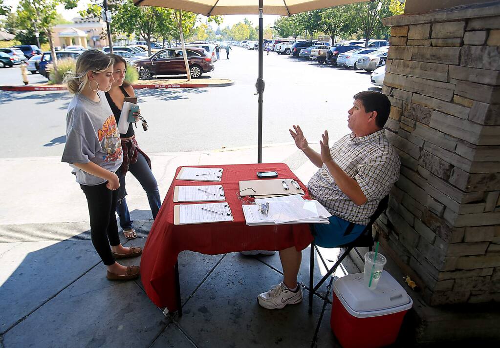 Declining to give his name, a petitioner talks to prospective signers about attempting to get Santa Rosa's rent control overturned, Wednesday Sept. 8, 2016 in front of Safeway on Mendocino Ave. in Santa Rosa. (Kent Porter / The Press Democrat) 2016