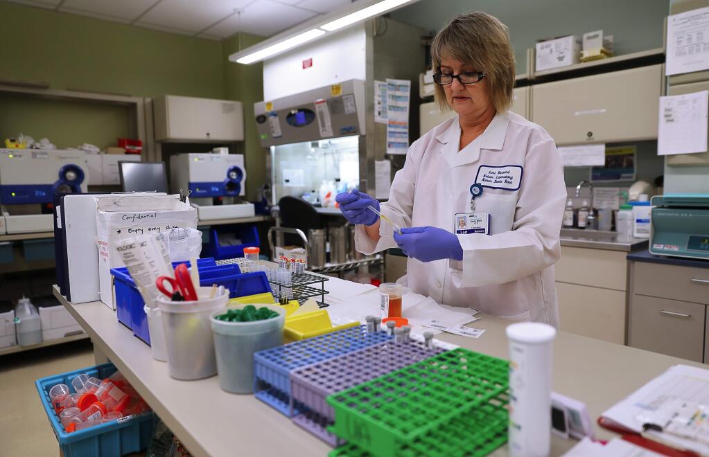 Clinical lab scientist Lori Rennard prepares a urine sample to be shipped off-site to be tested for chlamydia, at the urinalysis lab in Kaiser Permanente, in Santa Rosa on Friday, September 1, 2017. (Christopher Chung/ The Press Democrat)