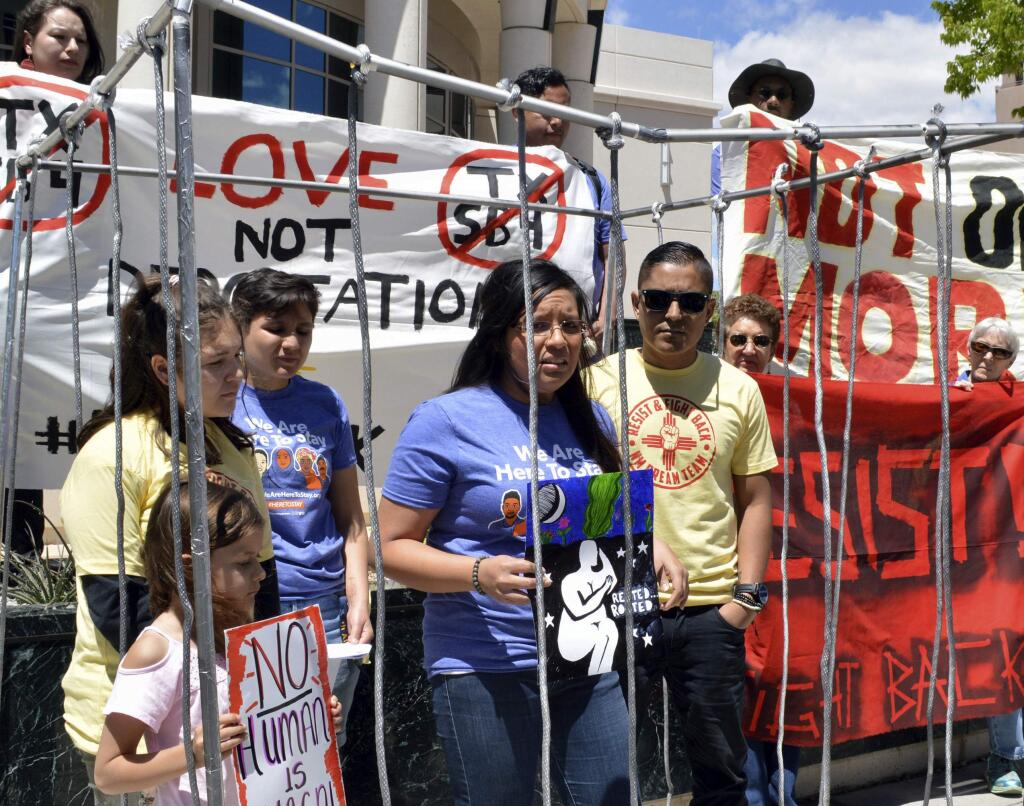 FILE - In this May 1, 2017 file photo, immigrant rights advocates speak out against immigration policies of President Donald Trump while placing themselves in mock detention in Albuquerque, N.M., to mark May Day. The U.S. Justice Department is including New Mexico's most populous county in an effort to pressure cities to cooperate with federal immigration authorities. Bernalillo County was one of roughly two dozen jurisdictions to receive warning letters Wednesday, Jan. 24, 2018, from the Justice Department. (AP Photo/Russell Contreras, File)