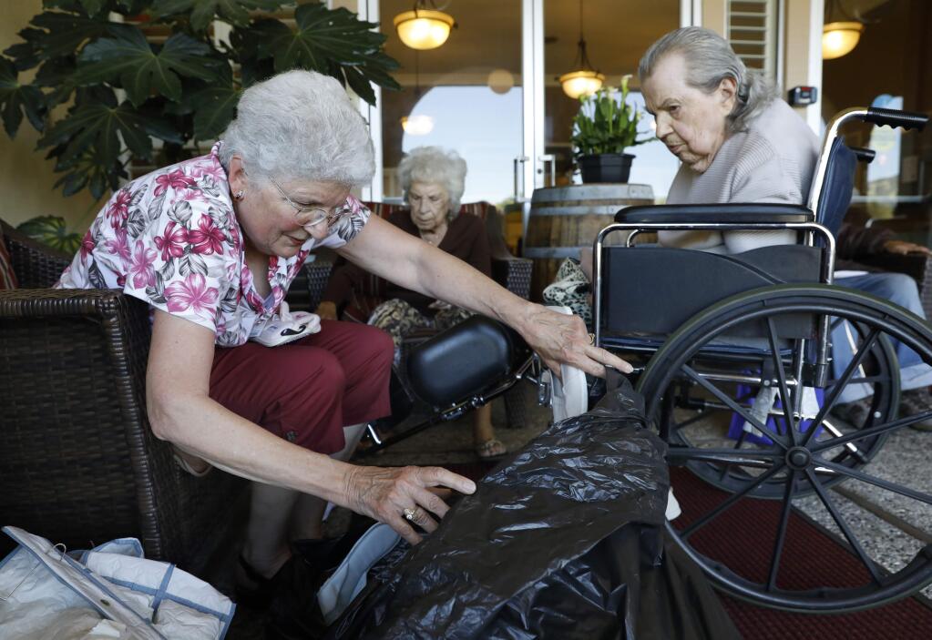 101-year-old Mabel Barnfield gets some help sorting through her shoes from her sister Betty James, center, and friend Marianne Dolan, left, at the Novato Healthcare Center in Novato, California on Wednesday, April 24, 2019. (BETH SCHLANKER/The Press Democrat)