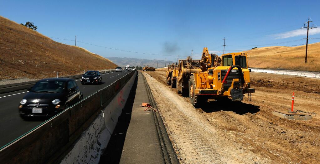 Motorists drive southbound on Highway 101 as wheel tractor-scrapers, right, grade the soil in the highway median, south of Petaluma, California in 2018. (Alvin Jornada/The Press Democrat)