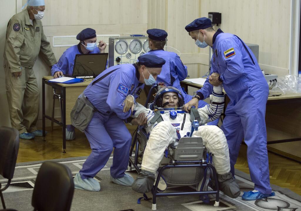 Russian Space Agency experts test a space suit of Japan astronaut Kimiya Yui, a crew member of the next mission to the International Space Station, prior to the launch of Soyuz-FG booster rocket with the space capsule Soyuz TMA-14M at the Russian leased Baikonur Cosmodrome, in Kazakhstan, Wednesday, July 22, 2015. (AP Photo/Pavel Golovkin)