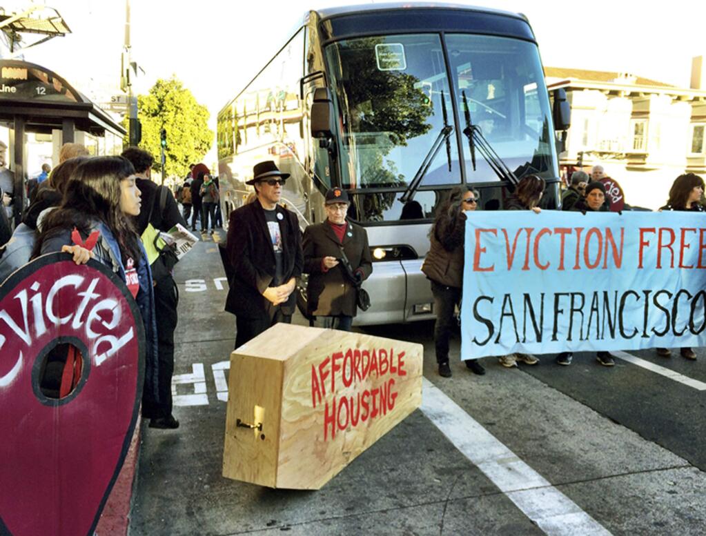 FILE - In this Dec. 20, 2013, file photo, anti-gentrification protesters temporarily block a shuttle bus full of tech workers at a Mission District public bus stop in San Francisco. Northern California authorities say multiple shuttle buses transporting Apple and Google employees had windows broken with unknown objects while traveling on a highway south of San Francisco on Tuesday, Jan. 16, 2018. Protesters in San Francisco, where tax incentives have lured tech firms, have previously targeted shuttle buses ferrying employees to and from Silicon Valley, saying technology workers were driving up rents and increasing the income divide. (Kurtis Alexander/San Francisco Chronicle via AP, File)