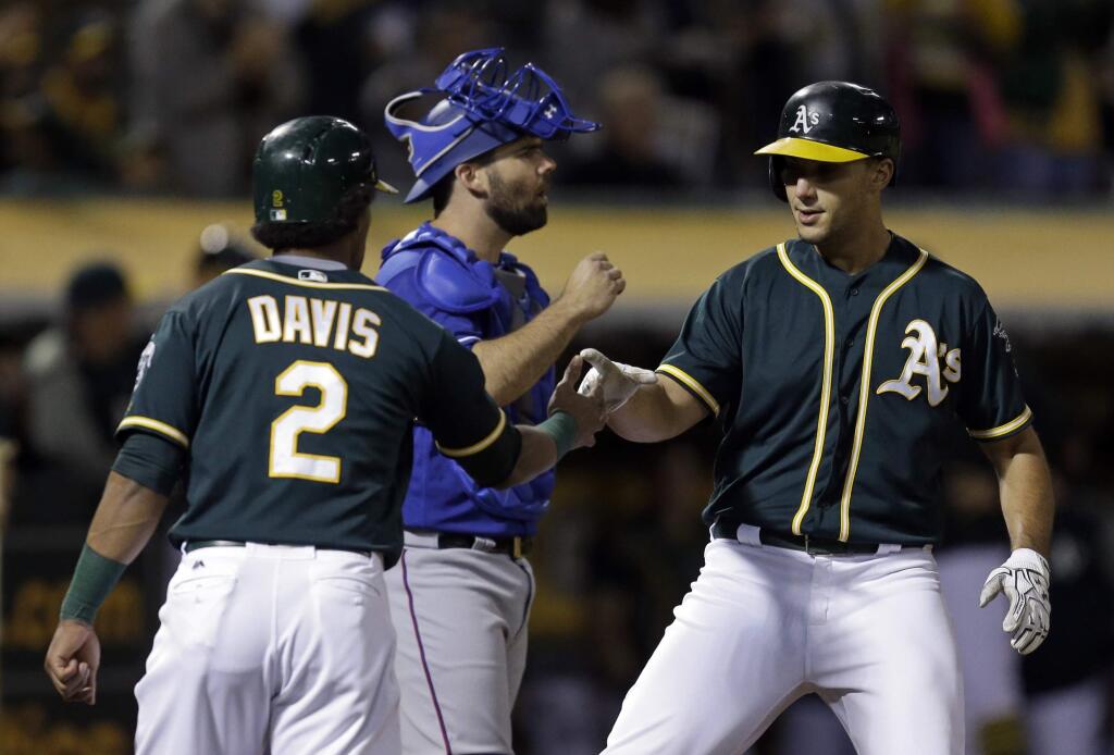 Oakland Athletics' Matt Olson, right, celebrates with Khris Davis (2) after hitting a two run home run off Texas Rangers' Nick Martinez in the second inning of a baseball game Friday, Sept. 22, 2017, in Oakland, Calif. (AP Photo/Ben Margot)