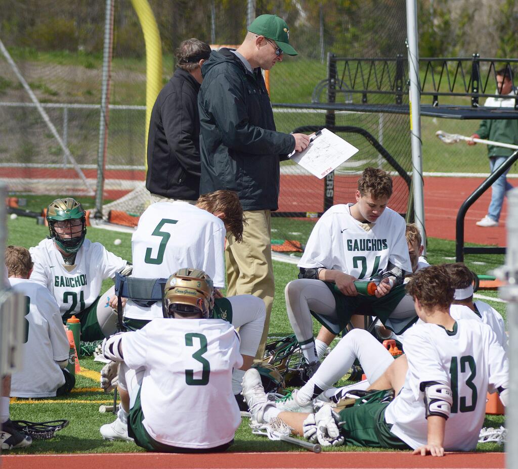 SUMNER FOWLER/FOR THE ARGUS-COURIERBen Hewitt checks his playbook as Casa Grande players review a game. Hewitt is leaving Casa Grande to become head lacrosse coach at Sonoma State.