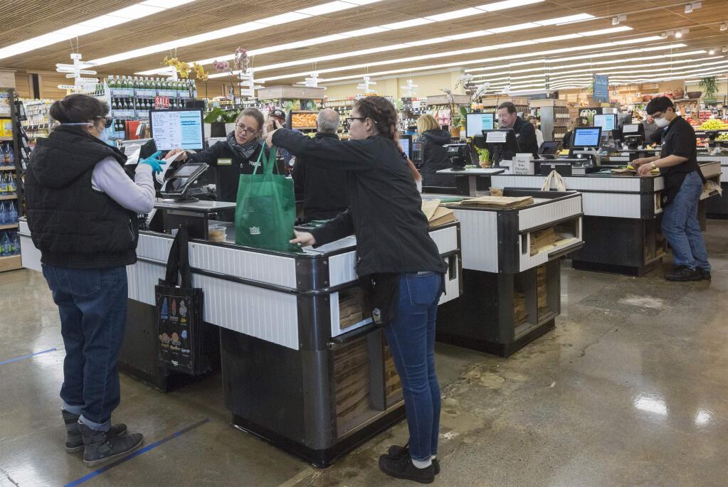 Cashiers and baggers at Sonoma Market are helping to provide an essential service, while putting themselves at obvious risk. (Photo by Robbi Pengelly/Index-Tribune)