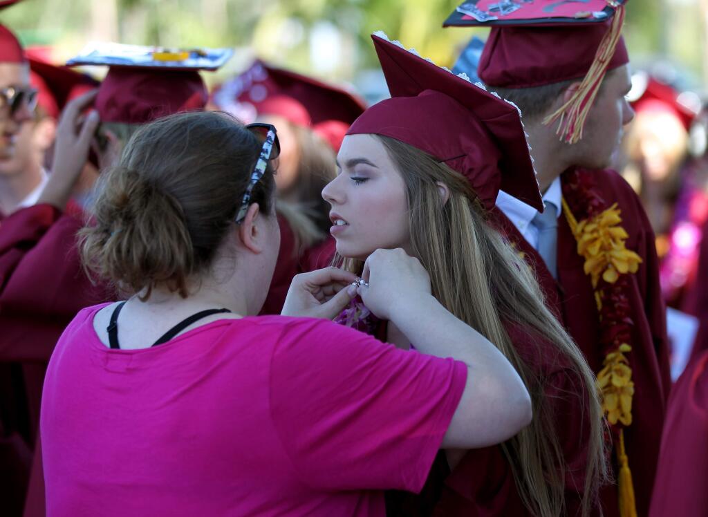 Graduate Clare O'Brien of Rohnert Park, has a necklace put on by her sister, Holly O'Brien, at the 50th Annual 2017 Cardinal Newman High School commencement in Santa Rosa, Calif., on Saturday, June 3, 2017. (Photo by Darryl Bush / For The Press Democrat)