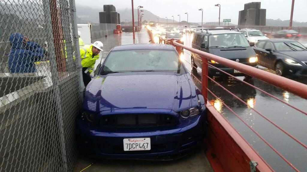 In this photo released by the Golden Gate Bridge Highway and Transportation District, a bridge worker looks over a car driven onto the pedestrian walkway of the Golden Gate Bridge Tuesday, Dec. 4, 2014, in San Francisco. (AP Photo/Golden Gate Bridge Highway and Transportation District)