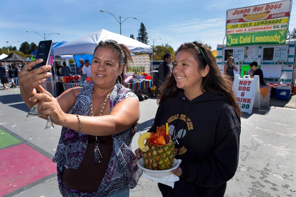 Rosa Linares and daughter, Celena Linares, 14, right, both of Ukiah, take a 'selfie' while getting ready to enjoy a 'fruta' during the Roseland Community Festival in Santa Rosa on Sunday October 1, 2017. (Photo by Darryl Bush / For The Press Democrat)