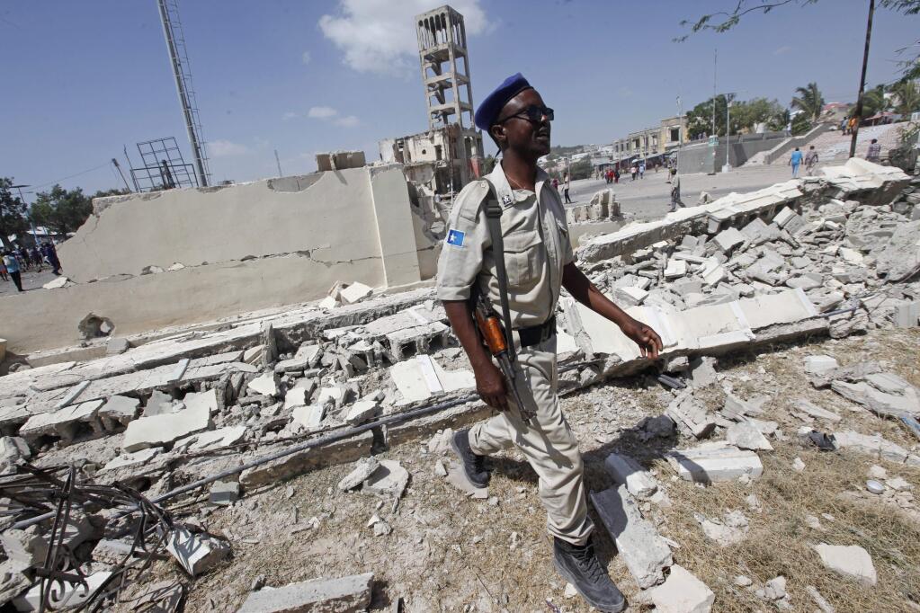 A police officer walks through the debris of a destroyed building following a large blast in Mogadishu, Somalia, Saturday, Dec. 22, 2018. Police say a suicide car bomb exploded near the presidential palace killing and injuring a number of people. (AP Photo/Farah Abdi Warsameh)