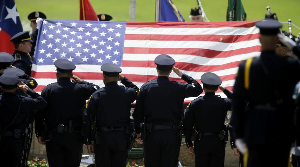 Members of an honor guard salute as the flag is lifted off of the coffin holding slain Dallas police officer Patrick Zamarripa during a ceremony Saturday at Dallas-Fort Worth National Cemetery. (LM OTERO / Associated Press)