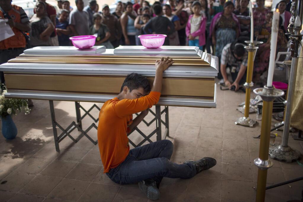 Francisco Davila mourns the death of his mother Maritza Nij Ramos Davila, 40, during her wake in Alotenango, Guatemala, Thursday, June 7, 2018. Guatemalan prosecutors have ordered an investigation into whether evacuation protocols were followed properly in Sunday's deadly volcanic eruption, which caught many residents unaware and with little to no time to evacuate. (AP Photo/Rodrigo Abd)