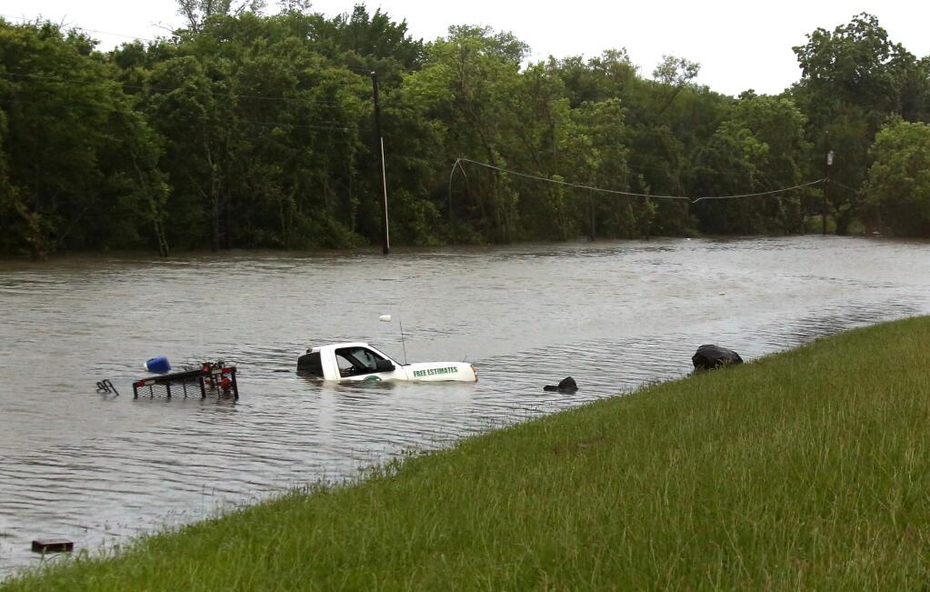 A truck rests near CF Hawn Freeway, Monday, May 25, 2015, in Dallas. The occupants escaped without harm after the truck was swamped by rising flood waters. Several people were reported missing in flash flooding from a line of storms that stretched from the Gulf of Mexico to the Great Lakes. (Louis DeLuca/The Dallas Morning News via AP)