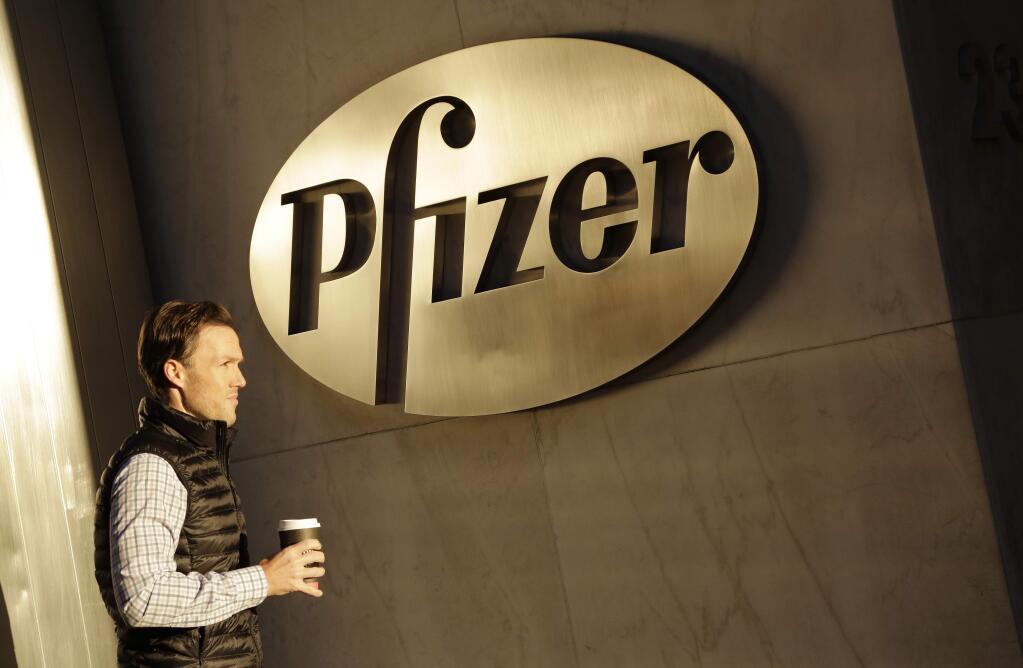 FILE - In this Monday, Nov. 23, 2015, file photo, a man enters Pfizer's world headquarters, in New York. Pfizer will not split into two publicly traded companies, a decision that, at least for now, ends Wall Street speculation over the drugmaker's future. The company believes it is best positioned to maximize shareholder value in its current form, but said Monday, Sept. 26, 2016, that it's reserving the right to split in the future if the situation changes. (AP Photo/Mark Lennihan, File)