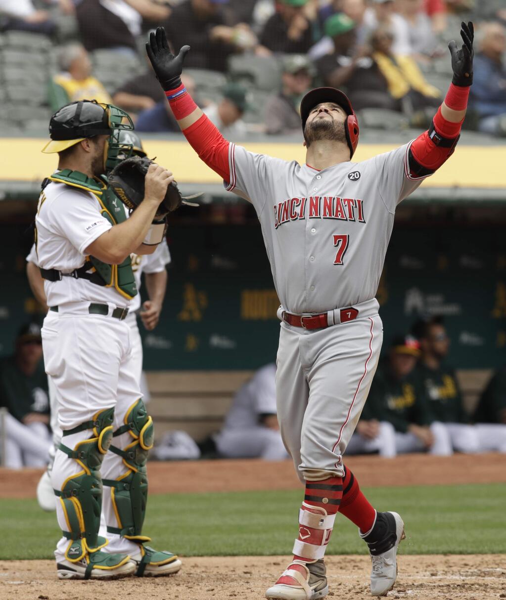 The Cincinnati Reds' Eugenio Suarez, right, celebrates as he crosses home plate after hitting a home run off the Oakland Athletics' Chris Bassitt in the third inning Thursday, May 9, 2019, in Oakland. (AP Photo/Ben Margot)