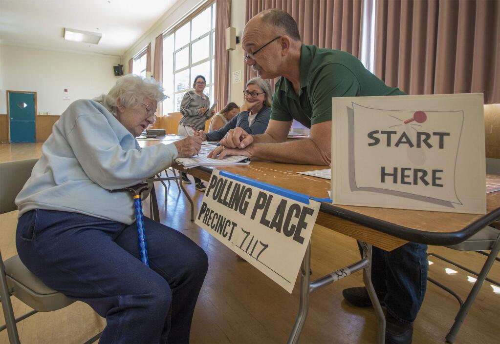 Ninety-six-year-old Mary Louise Mangiantini got a chair and some help from precinct clerk Dough Boss, when she came into the Vets Building to cast her vote last year. (Photo by Robbi Pengelly/Index-Tribune)