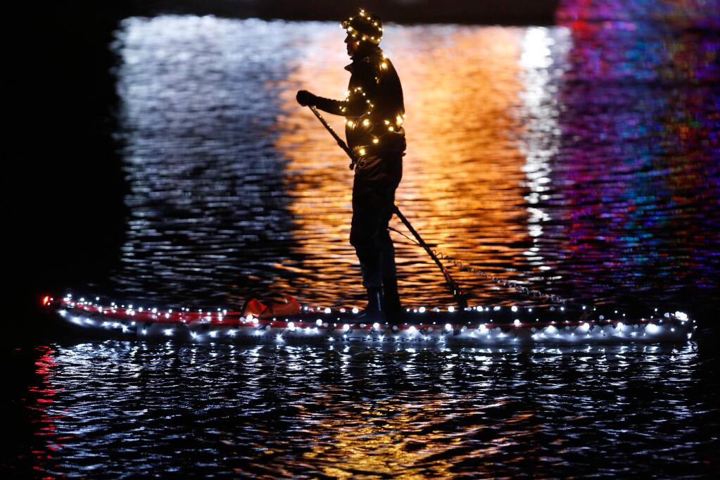 A stand-up paddleboarder clad in lights floats in the Petaluma River before the Lighted Boat Parade in Petaluma, California on Saturday, December 5, 2015. (Alvin Jornada / The Press Democrat)