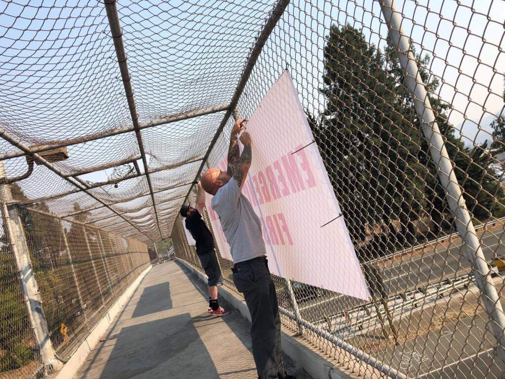 People hang signs on a Highway 101 overpass in Santa Rosa, thanking emergency personnel and first responders. (Joseph Wong)