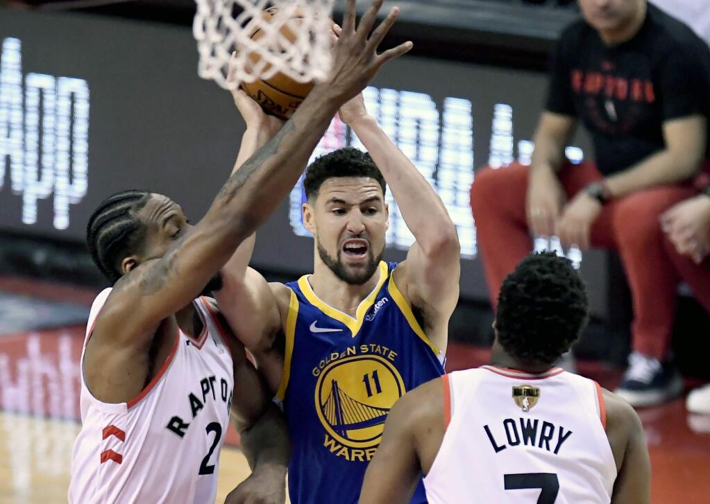 Golden State Warriors guard Klay Thompson (11) looks for the pass under pressure from Toronto Raptors guard Kyle Lowry (7) and teammate Kawhi Leonard (2)during the first half of Game 2 of basketball's NBA Finals, Sunday, June 2, 2019, in Toronto. (Frank Gunn/The Canadian Press via AP)