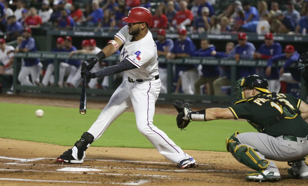 The Texas Rangers' Nomar Mazara, left, hits a two-run single in front of Oakland Athletics catcher Josh Phegley during the first inning in Arlington, Texas, Friday, Sept. 29, 2017. The Rangers' Shin-Soo Choo and Elvis Andrus scored on the play. (AP Photo/LM Otero)