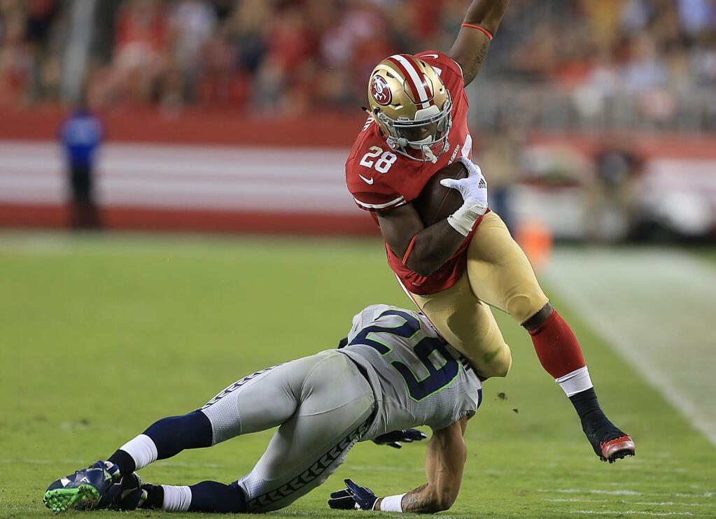 Carlos Hyde is tripped up by Seattle's Earl Thomas during the third quarter, Thursday Oct. 22, 2015. (Kent Porter / Press Democrat)