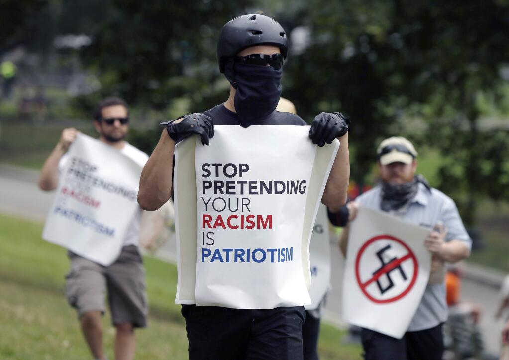 Counterprotesters hold signs before conservative organizers begin a planned 'Free Speech' rally on Boston Common, Saturday, Aug. 19, 2017, in Boston. Police Commissioner William Evans said Friday that 500 officers, some in uniform, others undercover, would be deployed to keep the two groups apart. (AP Photo/Michael Dwyer)