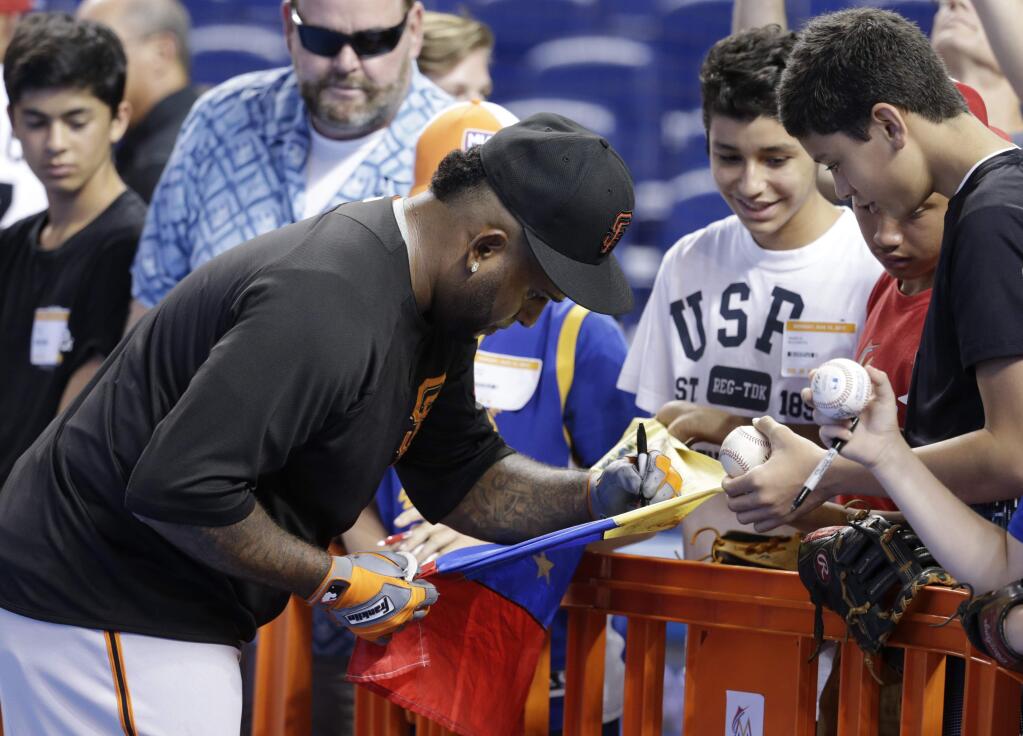 San Francisco Giants third baseman Pablo Sandoval signs a Venezuelan flag for fans before a baseball game against the Miami Marlins, Monday, Aug. 14, 2017, in Miami. (AP Photo/Lynne Sladky)
