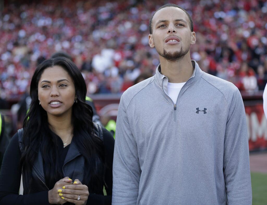 FILE - In this Nov. 10, 2013, file photo, Golden State Warriors player Stephen Curry, right, and his wife Ayesha Curry watch as the San Francisco 49ers play the Carolina Panthers during the third quarter of an NFL football game in San Francisco. (AP Photo/Marcio Jose Sanchez, File)