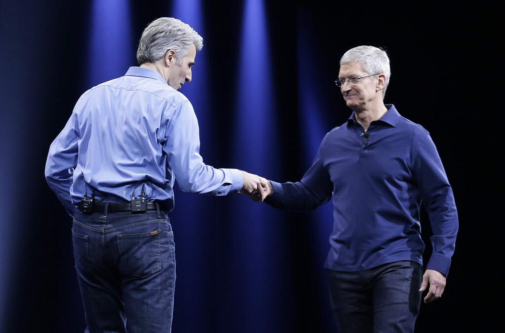 Craig Federighi, Apple senior vice president of Software Engineering, left, shakes hands with Apple CEO Tim Cook at the Apple Worldwide Developers Conference in San Francisco, Monday, June 8, 2015. (AP Photo/Jeff Chiu)