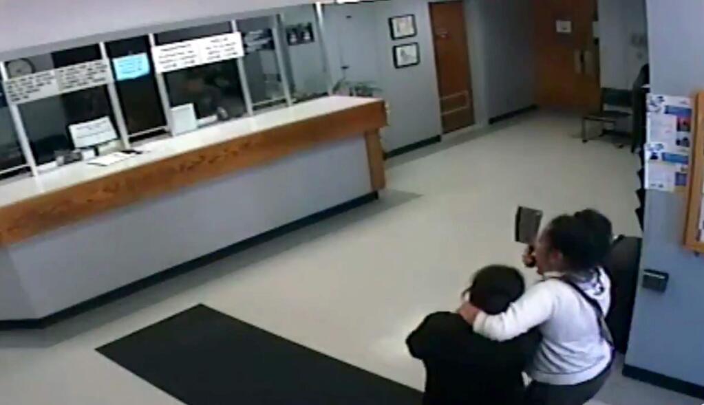 This Wednesday, Sept. 25, 2019 photo taken from surveillance video posted on Twitter and released by the Salinas Police Department shows a woman armed with a meat cleaver taking another woman hostage in the lobby of the Salinas Police Department in Salinas, Calif. Assistant Chief Roberto Filice tells The Californian officers ordered her to drop the meat cleaver and the victim was able to escape. He says an officer then used a stun gun on the suspect once, incapacitating her. (Salinas Police Department via AP)