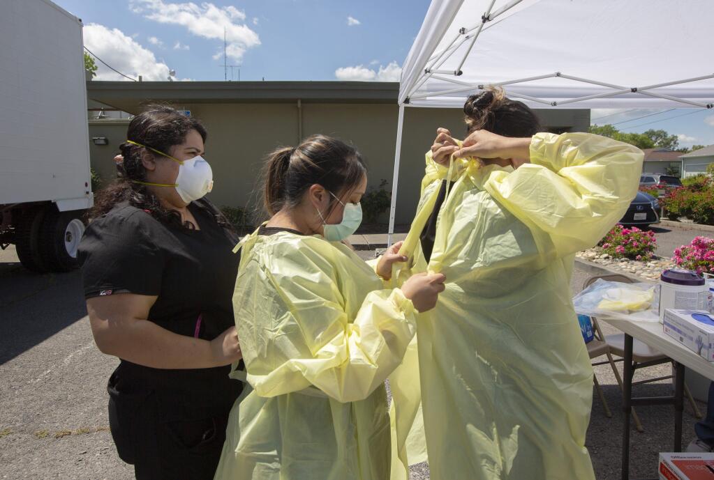 Health workers help each other with their PPE. The Sonoma Valle Community Health Center began free Covid-19 testing at the Sonoma Valley Hospital on Wednesday, May 20. (Photo by Robbi Pengelly/Index-Tribune)